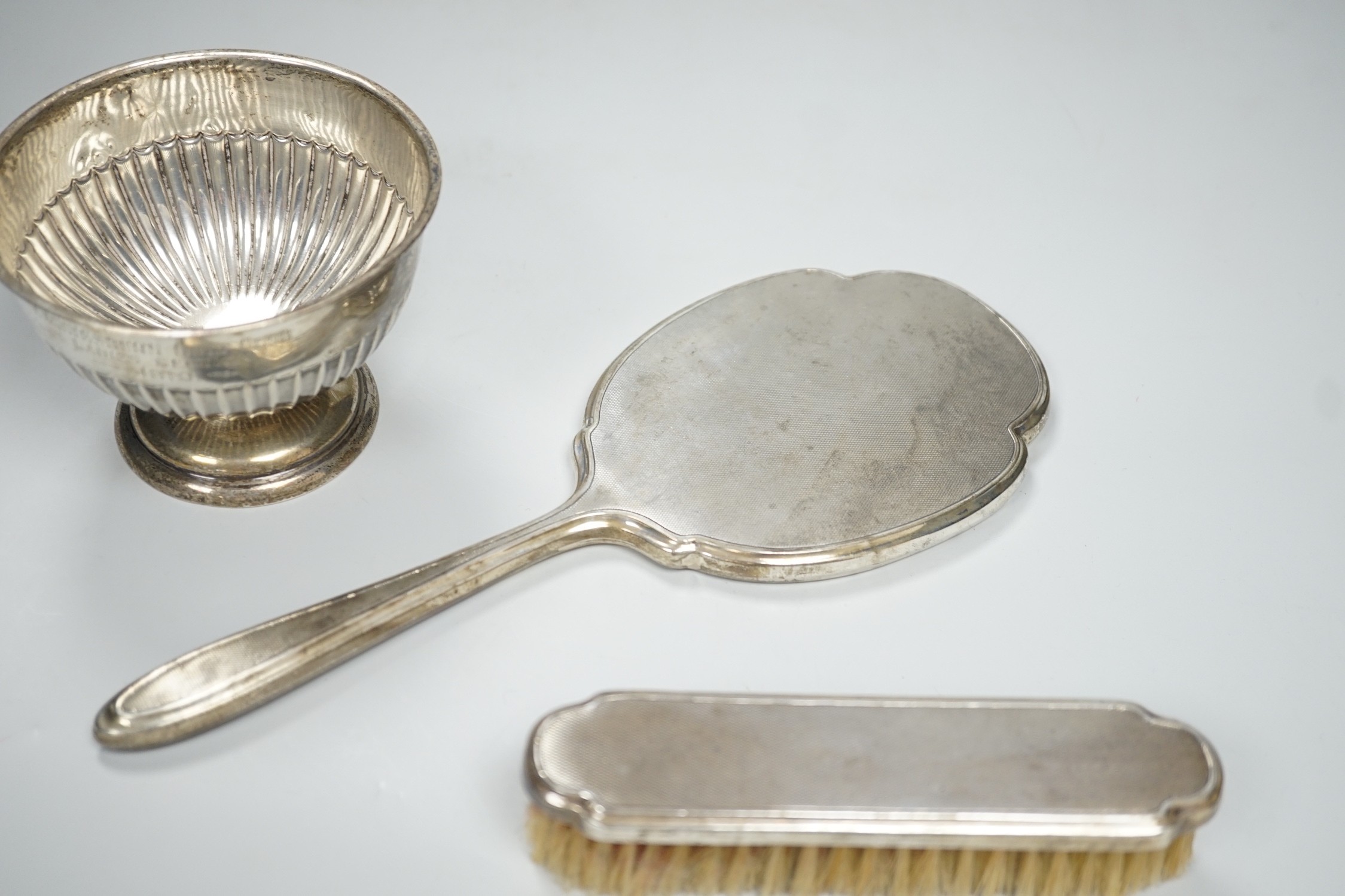An Edwardian demi-fluted silver small presentation pedestal bowl, Sheffield, 1904, diameter 10.9cm and a silver mounted hand mirror and clothes brush.